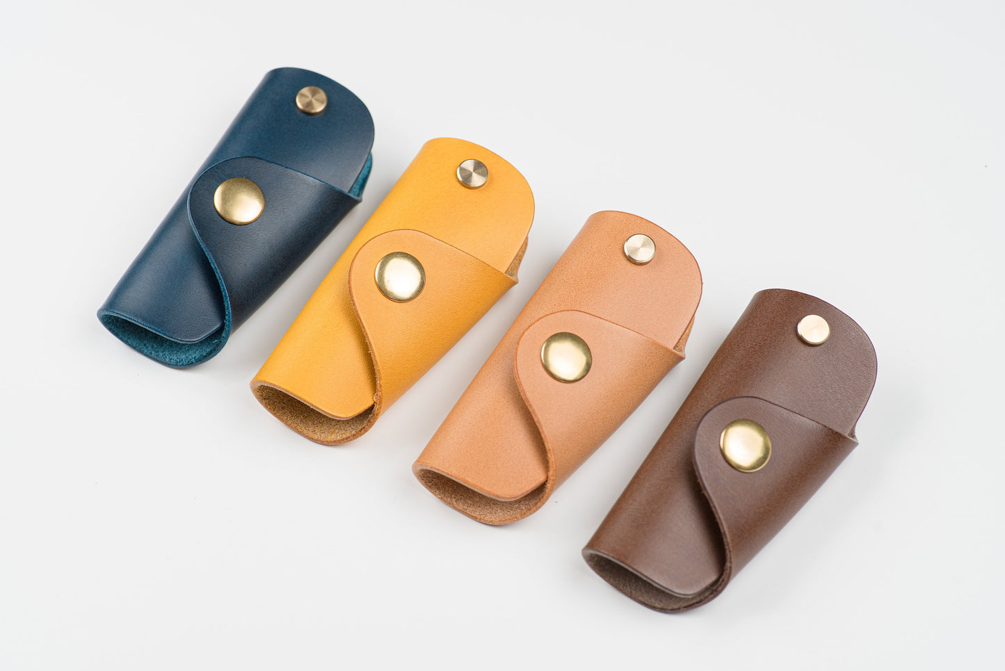 4 Buttero Leather Key Case in navy blue, mustard yellow, pink and brown color with brass hardware and a removable brass wire hook.
