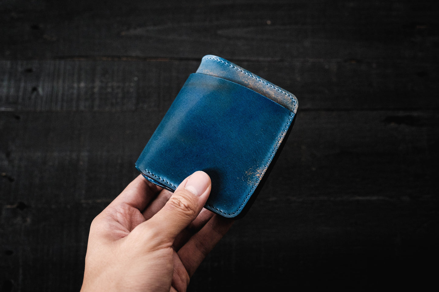 A person holding a blue Rocado Shell Cordovan Contour Billfold Wallet