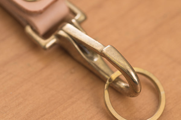 A natural leather key holder with a solid brass hardware and snap, close up of  solid brass snap