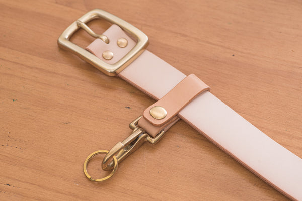 A natural leather key holder with a solid brass hardware and snap put on belt. lifestyle view