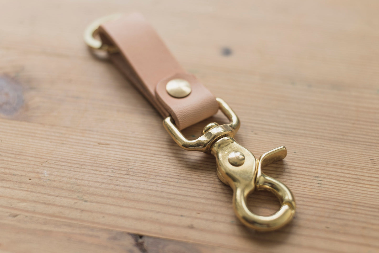A natural leather key holder with a solid brass Chicago screw and trigger snap, close up of trigger snap