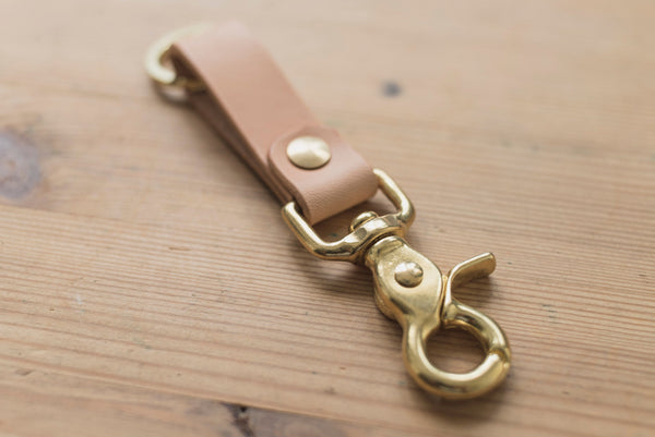 A natural leather key holder with a solid brass Chicago screw and trigger snap, close up of trigger snap