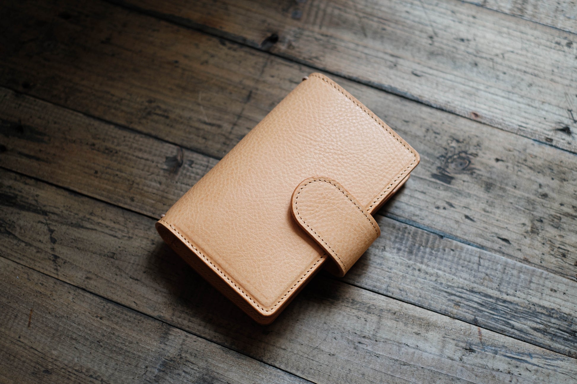 A natural lined traveler's notebook with card slots and a leather strap, displayed close