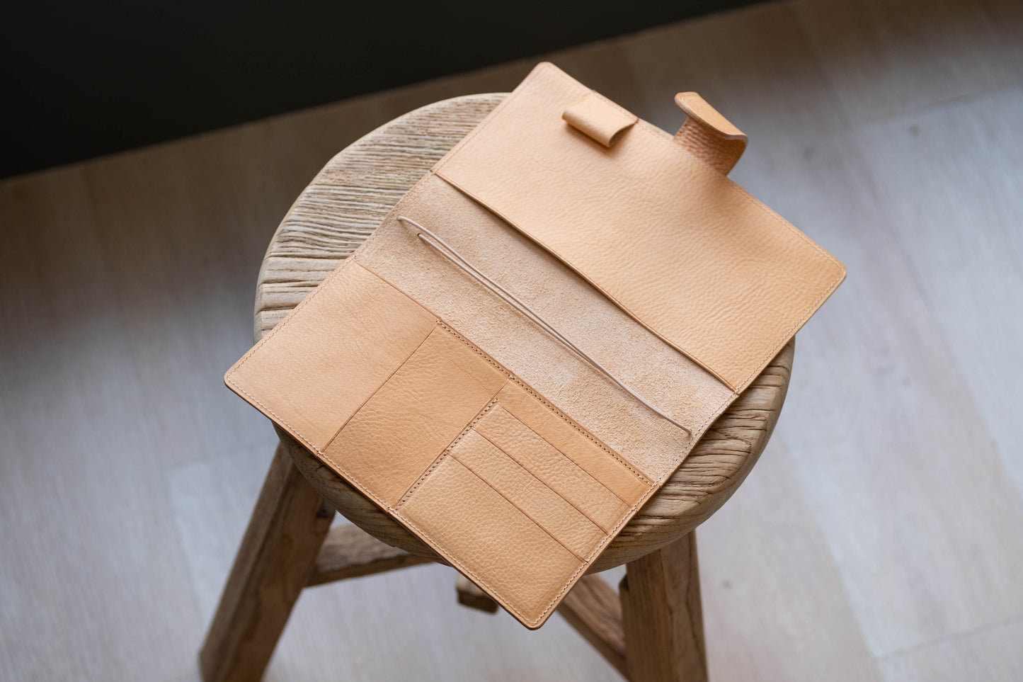 A natural leather traveler's notebook with card slots and a snap button closure, displayed open