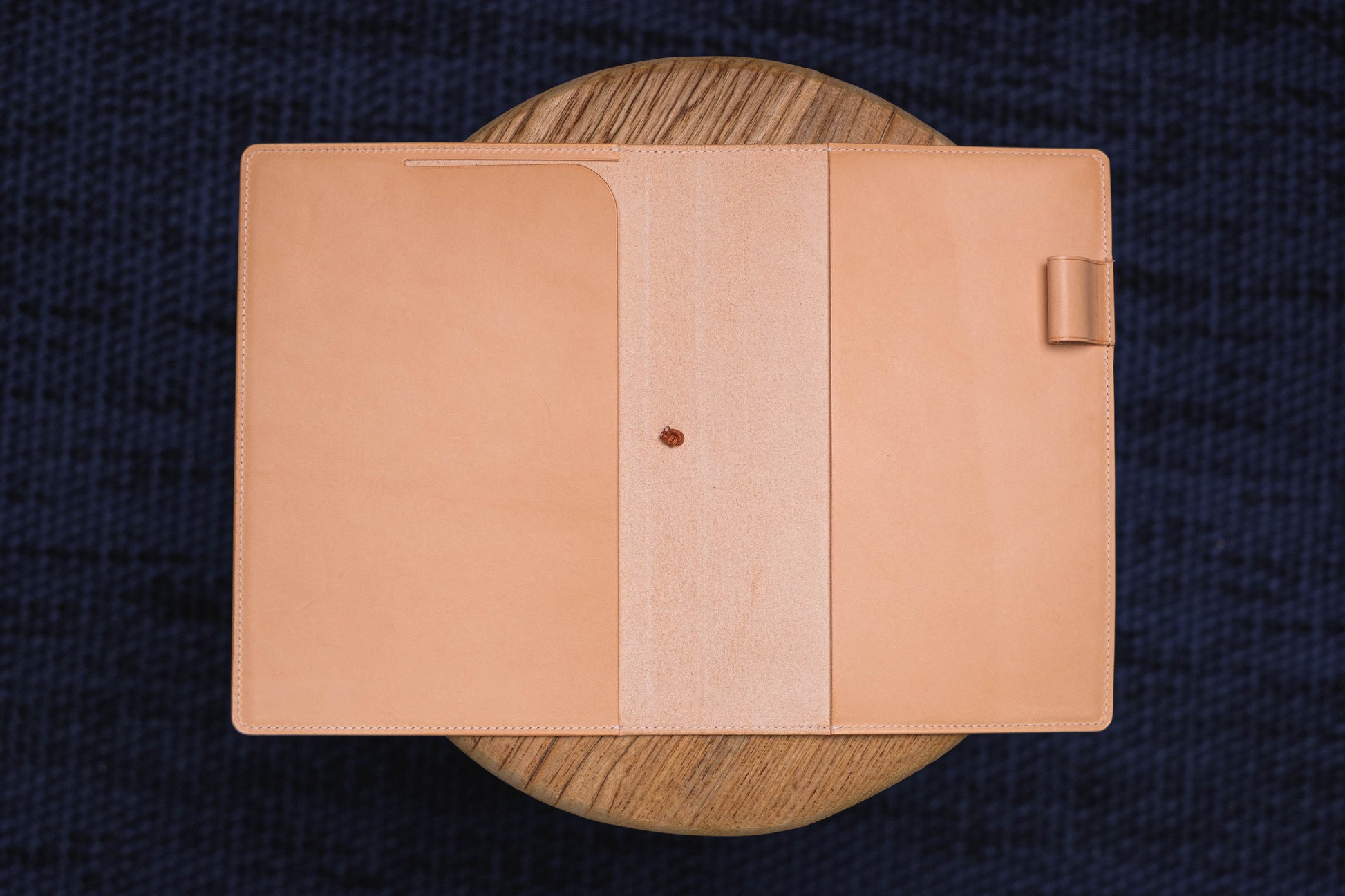  A natural leather notebook cover with a pen holder on the right side. The cover is open.