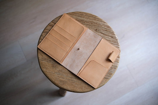 A natural pebbled leather notebook cover with elastic closure and card slots.
