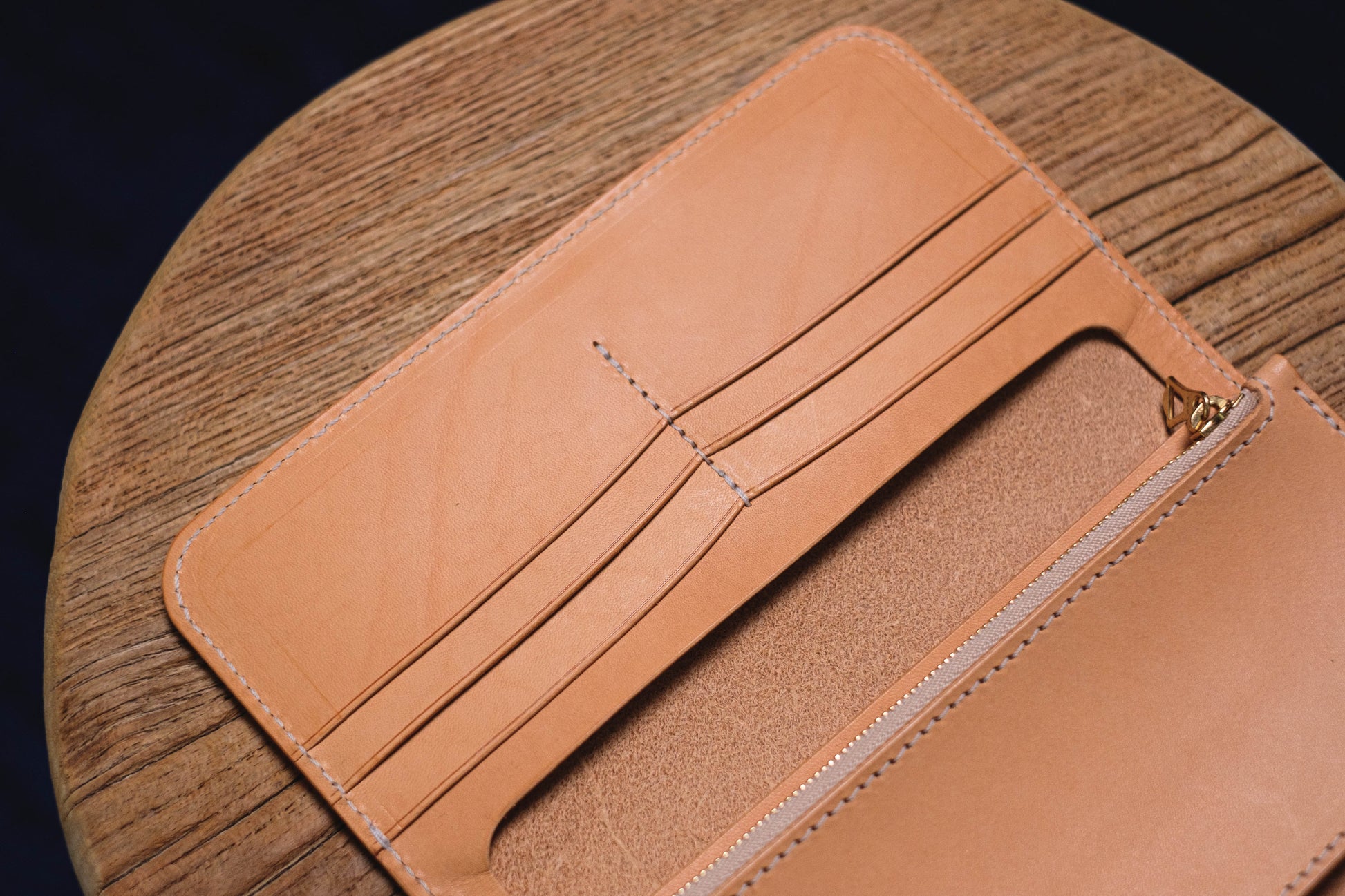 A natural leather wallet with 6 card slots and a zippered compartment. The wallet is open.