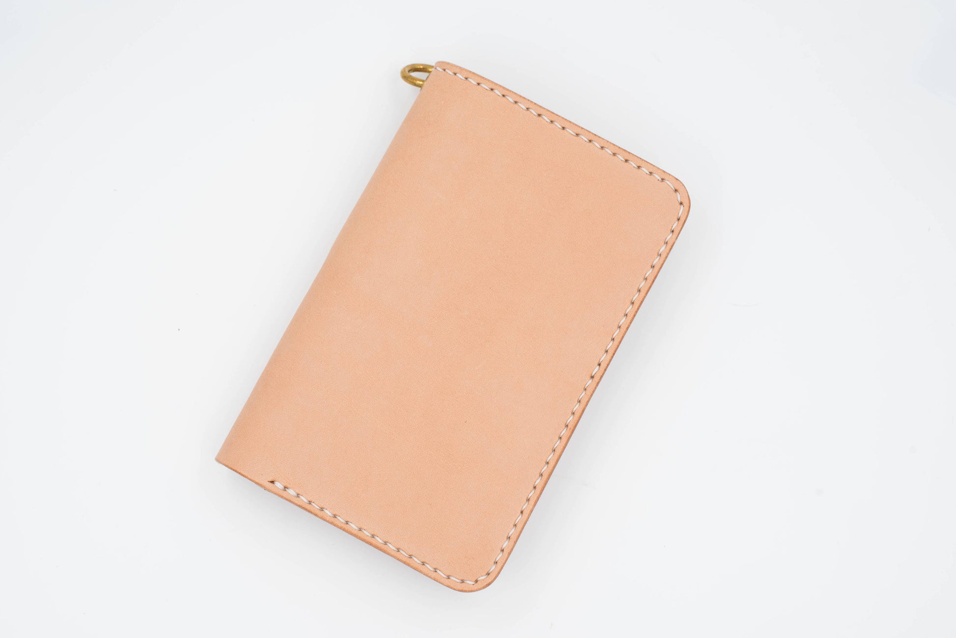 A natural leather wallet with a brass clasp. The wallet has white stitching around the edges.