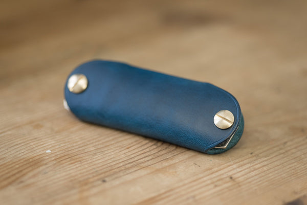 Navy blue leather key holder with brass snaps and screws, back view