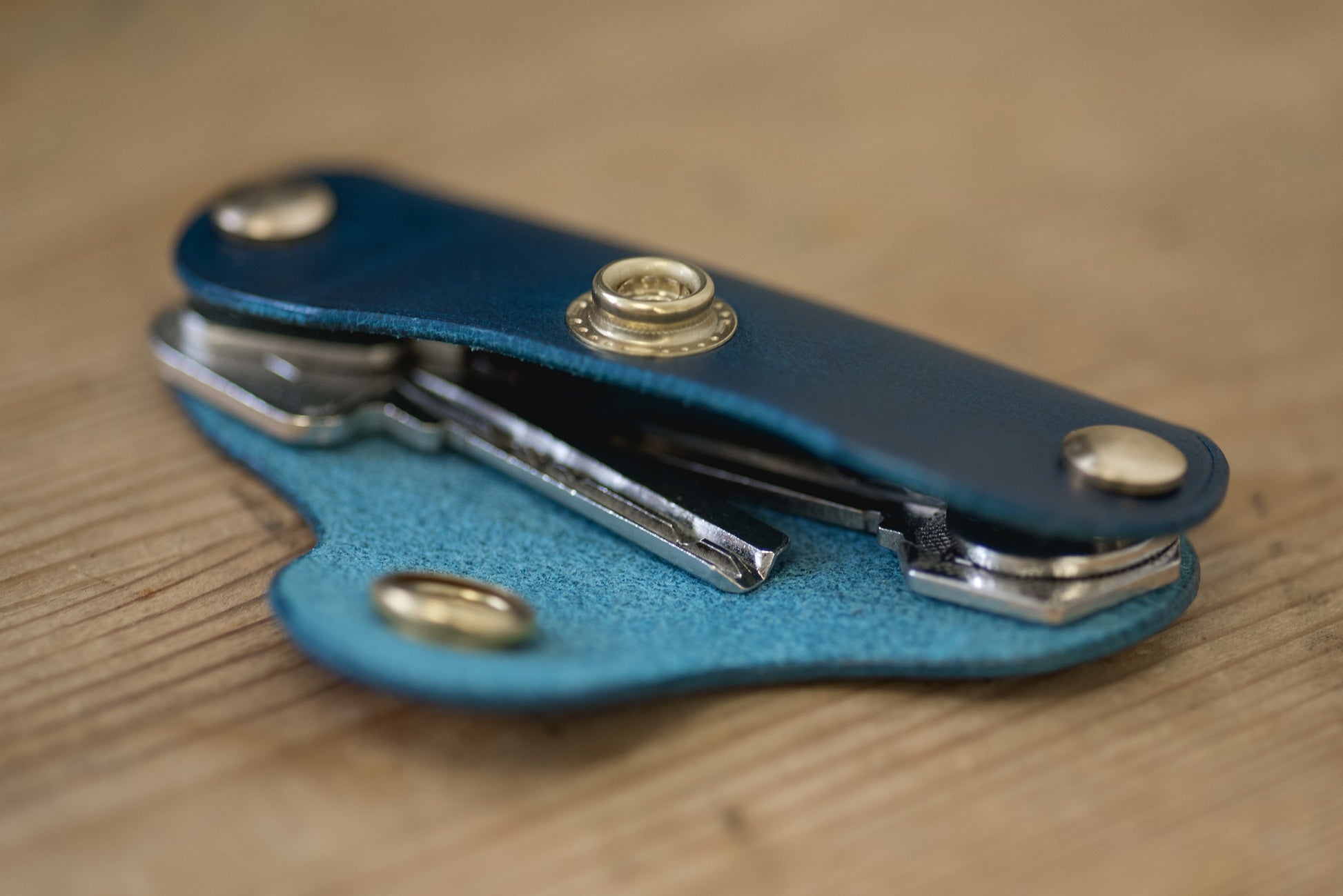 Navy blue leather key holder with brass snaps and screws, side view with keys