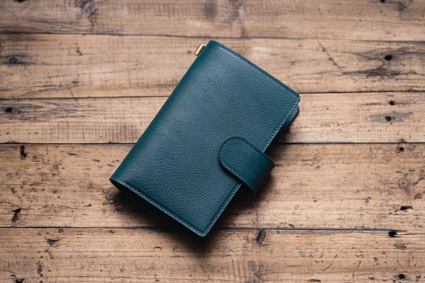 A navy blue leather traveler's notebook with card slots and a snap button closure, displayed closed