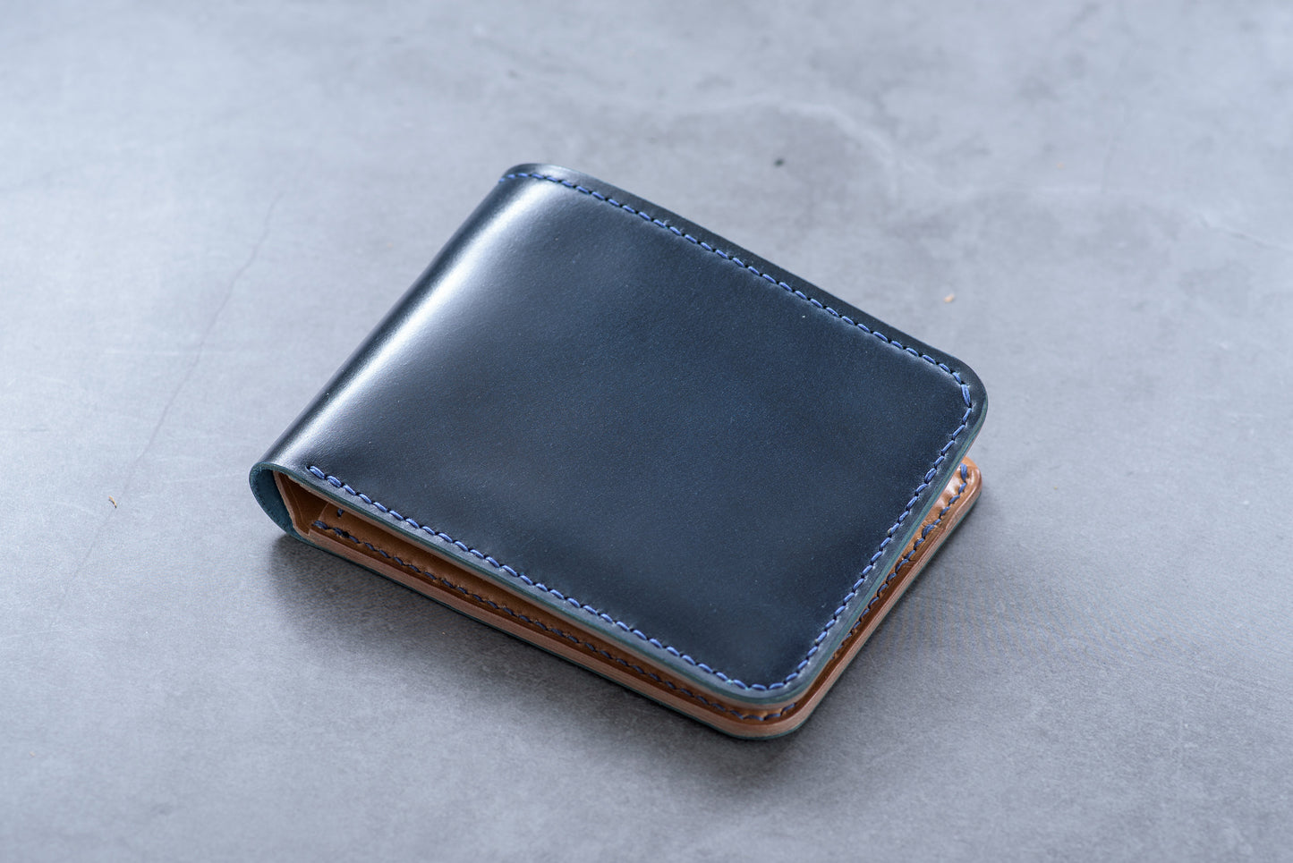a navy blue and whiskey shell cordovan leather billfold wallet with blue stitching