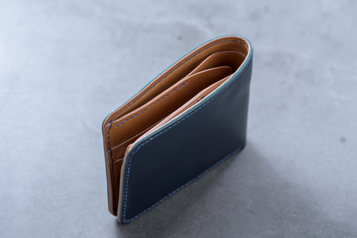 a navy blue and whiskey shell cordovan leather billfold wallet with blue stitching - top view