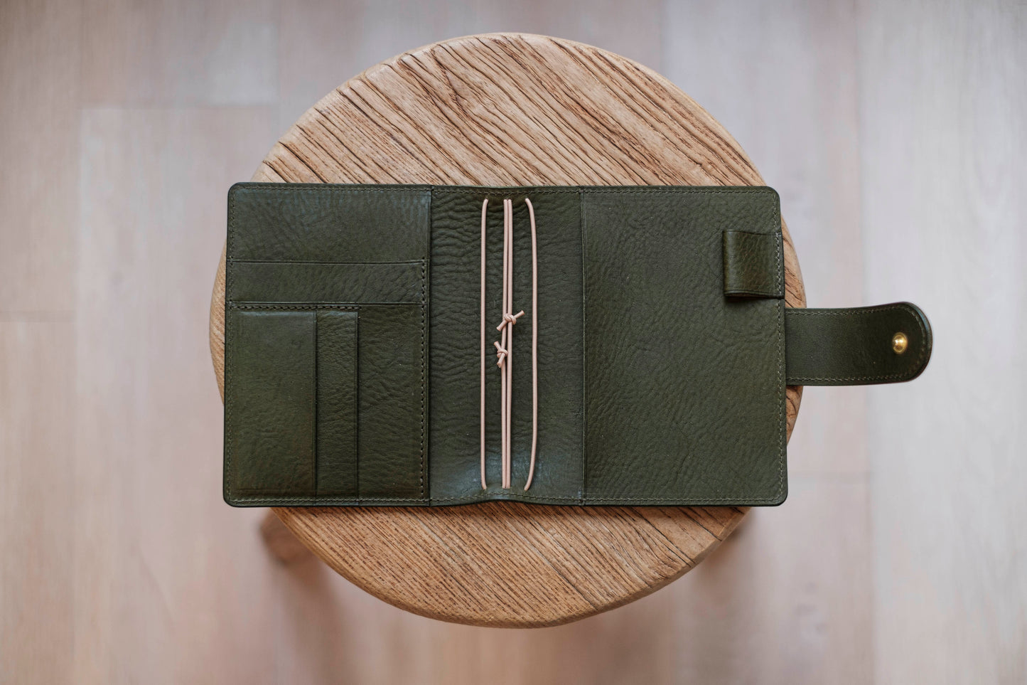 A olive green lined traveler's notebook with card slots and a leather strap, displayed open - detail