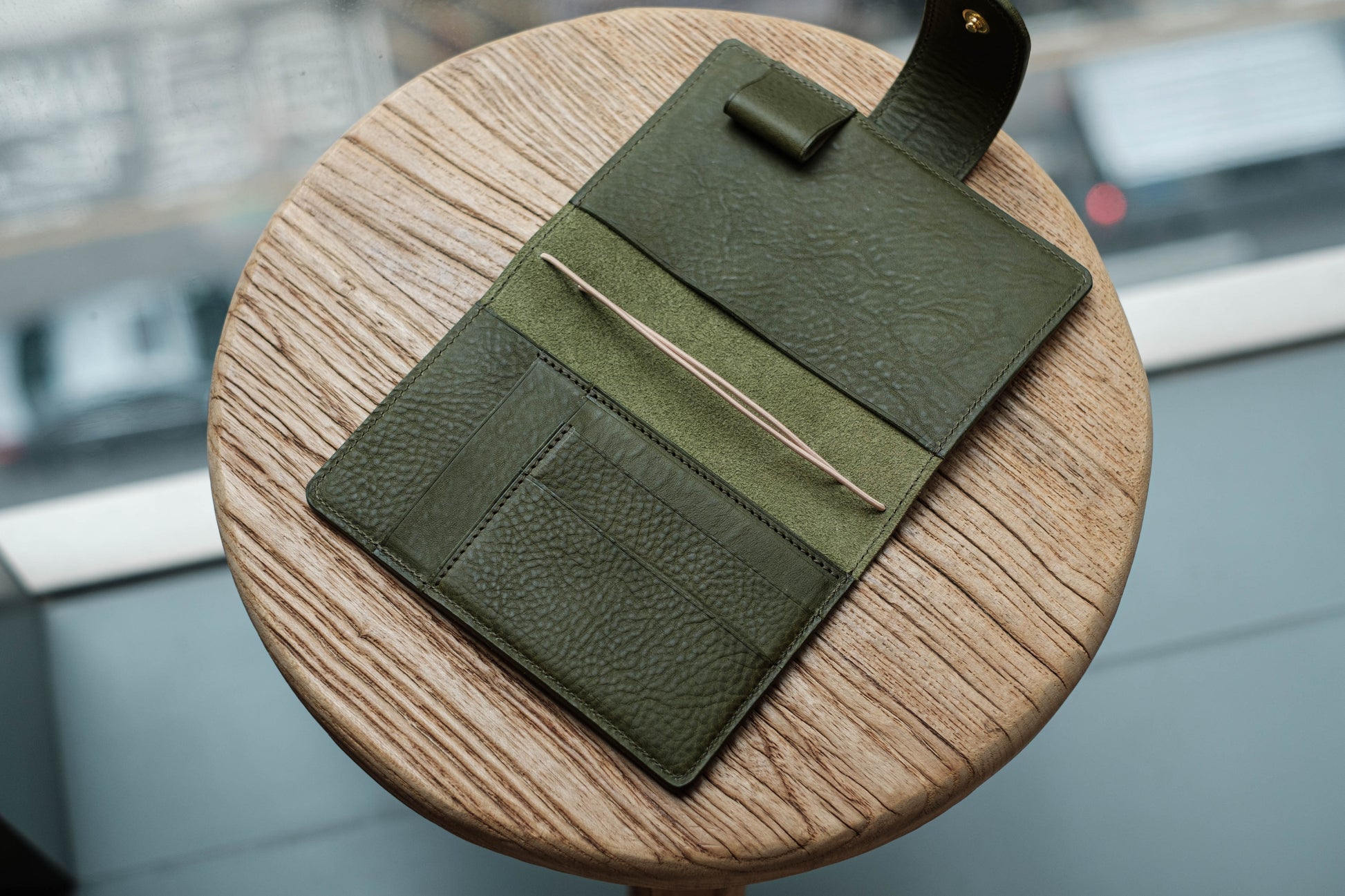 A olive green leather traveler's notebook with card slots and a snap button closure, displayed open