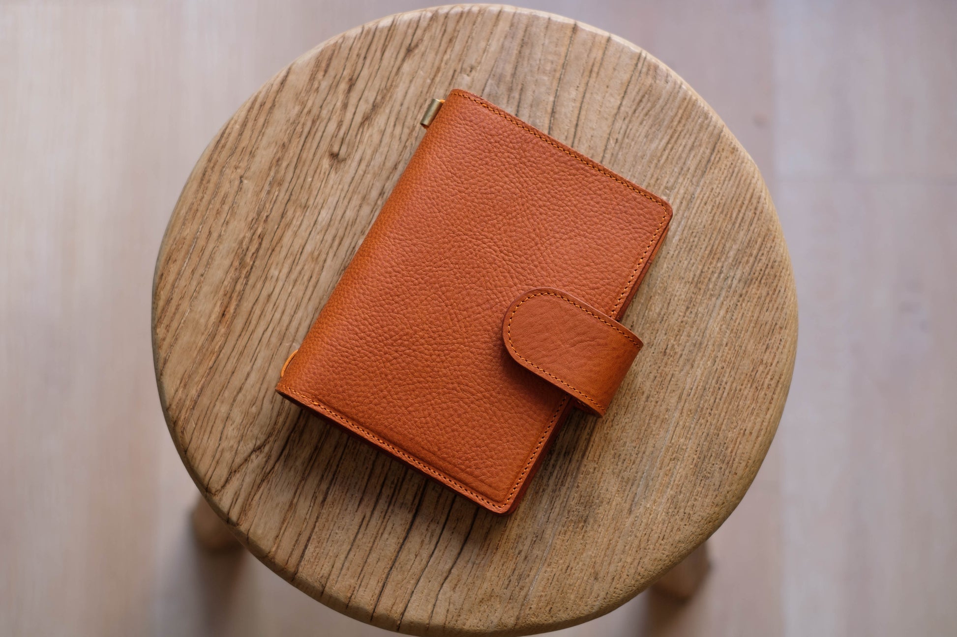 A brown leather traveler's notebook with card slots and a snap button closure, displayed closed