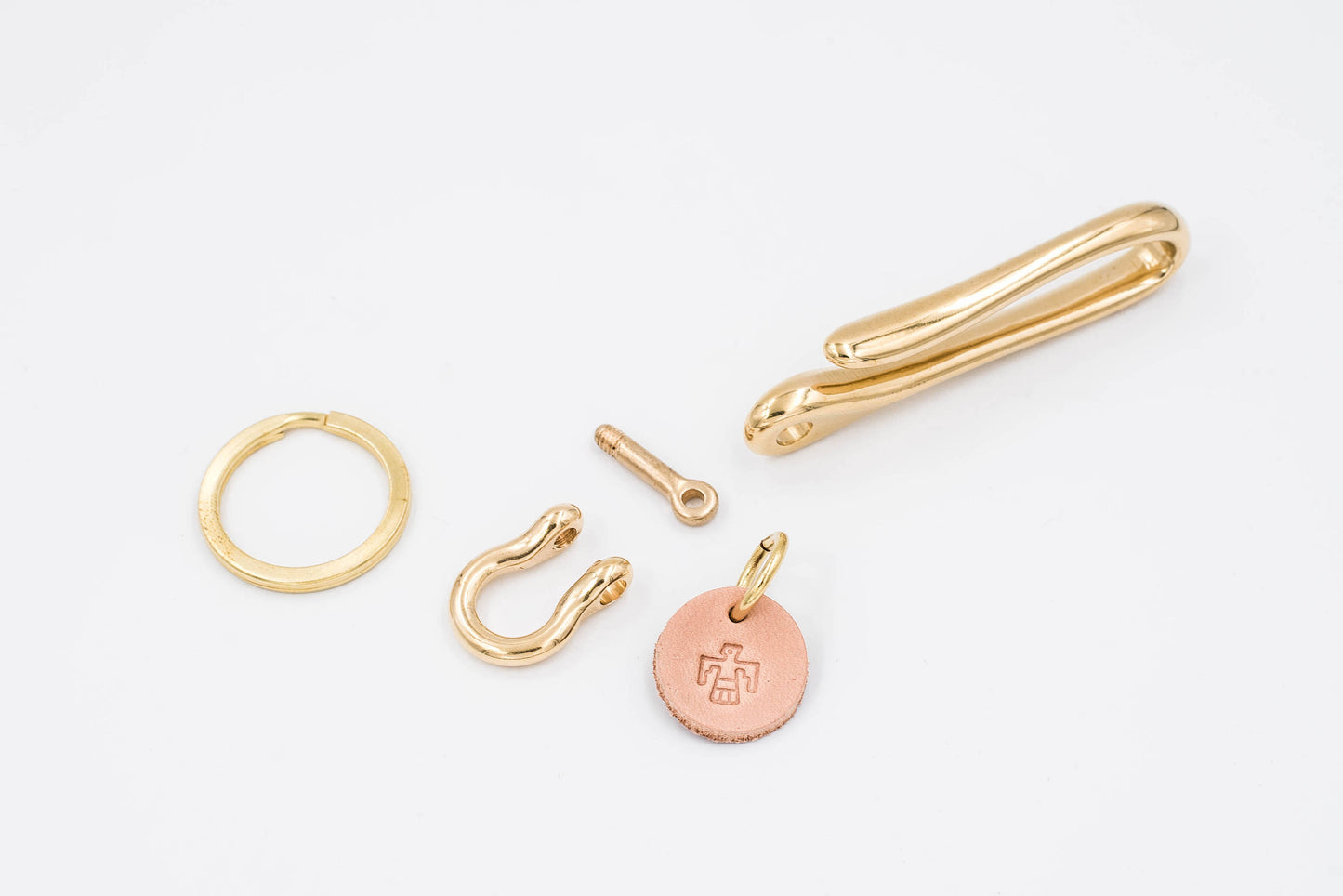 The component of gold-colored brass fish hook key holder with a leather tag and solid brass key ring.