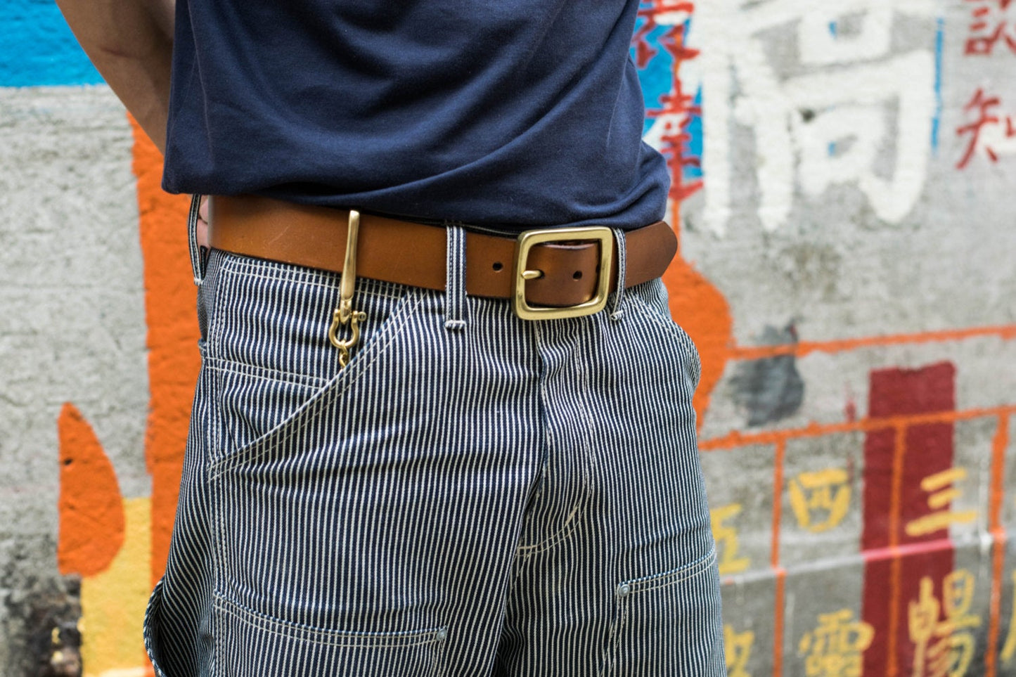 Person wearing a Tan Leather Garrison Belt with denim jeans match with Solid Brass Key Rein with Fish Hook