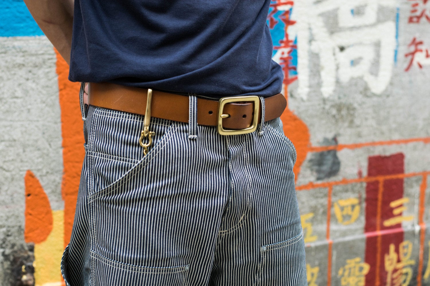Person wearing a Tan Leather Garrison Belt with denim jeans match with Solid Brass Key Rein with Fish Hook