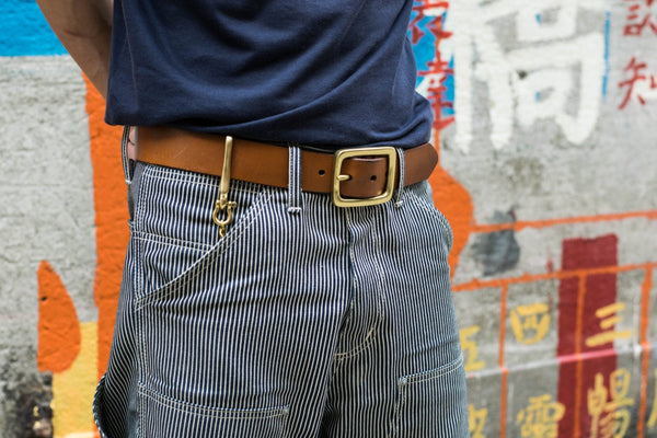 Person wearing a Tan Leather Garrison Belt with denim jeans match with Solid Brass Key Rein with Fish Hook