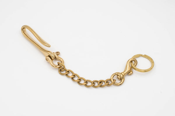 A polished brass fish hook with a solid brass chain attached to a key ring, designed to be hooked to a belt or belt loop.