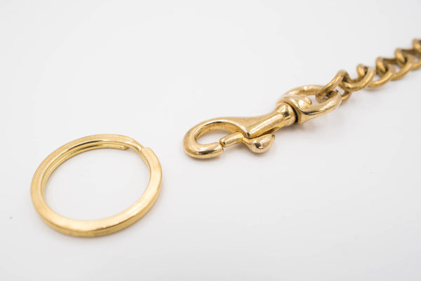 A polished brass keychain with a trigger snap, close up of key ring