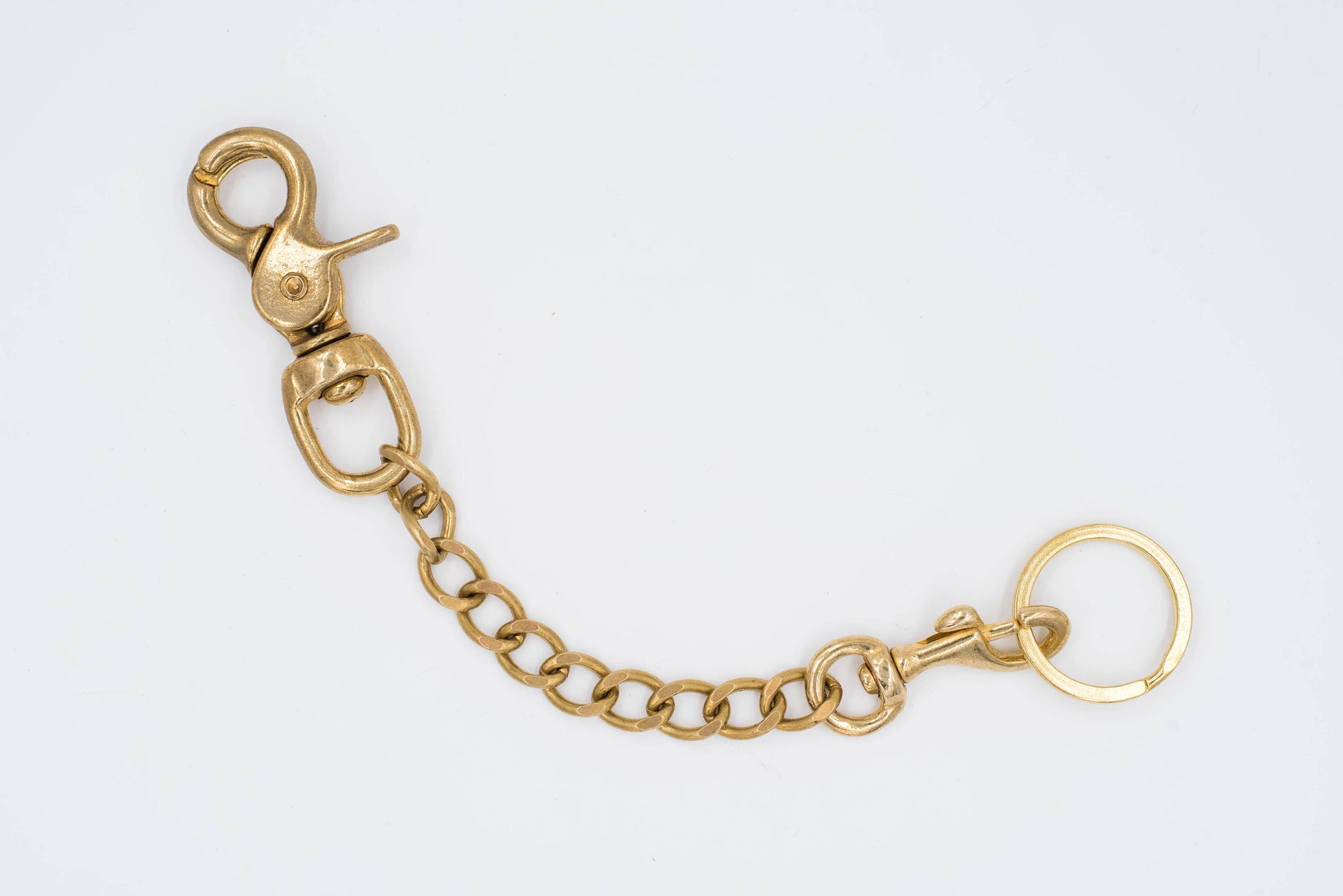 A polished brass Trigger Snap with a solid brass chain attached to a key ring, designed to be hooked to a belt or belt loop.
