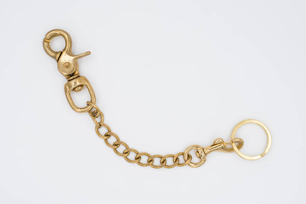 A polished brass Trigger Snap with a solid brass chain attached to a key ring, designed to be hooked to a belt or belt loop.