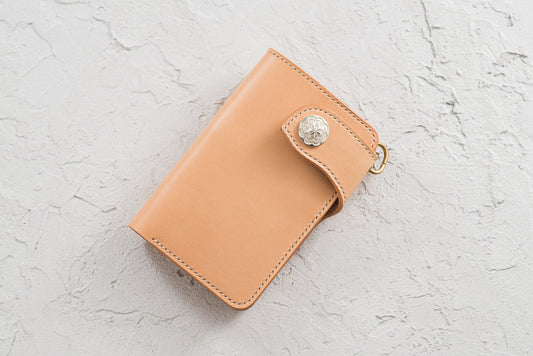 A natural leather middle billfold wallet for men with a sterling silver concho and a snap closure.