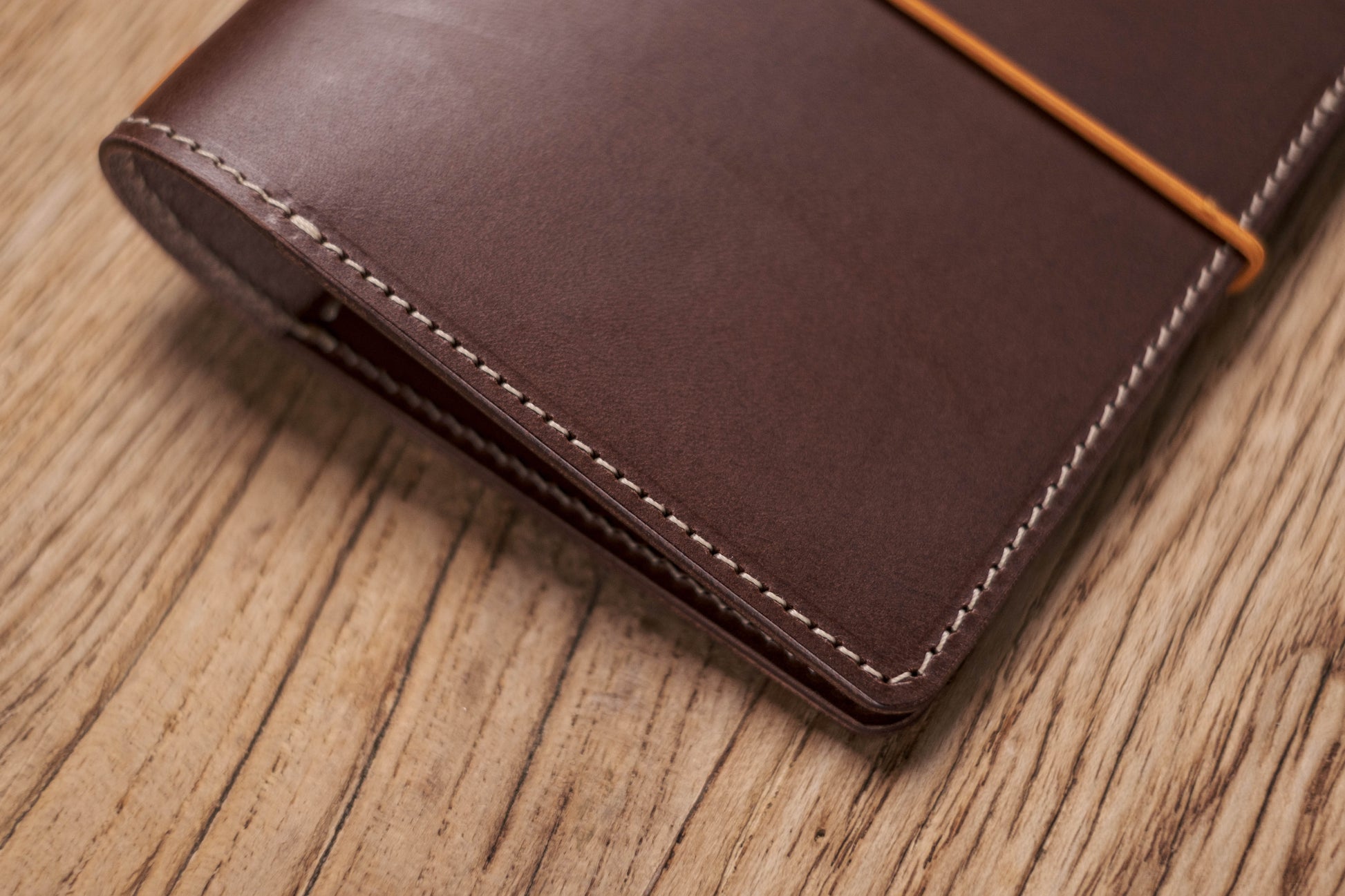 A brown Stitched Buttero Leather Traveler's Notebook and a elastic enclouse, Close up of stitching