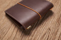 A brown Stitched Buttero Leather Traveler's Notebook and a elastic enclouse, Close up of elastic enclouse and stitching