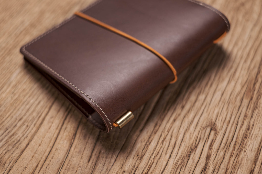 A brown Stitched Buttero Leather Traveler's Notebook and a elastic enclouse, Close up of elastic enclouse and stitching