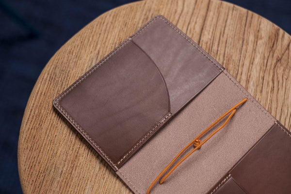 A brown Stitched Buttero Leather Traveler's Notebook and a elastic enclouse, displayed open, close up for inside left pocket