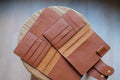 Two orange brown leather traveler's notebook with card slots and a snap button closure, displayed open