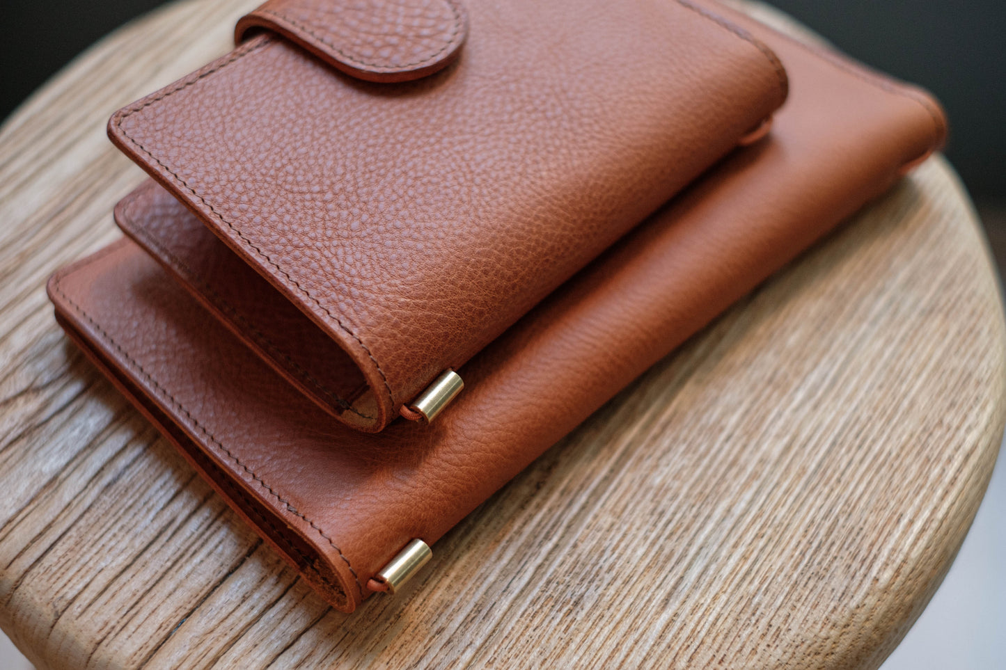 Two brown leather traveler's notebook with card slots and a snap button closure, displayed closed