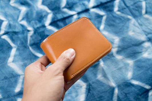 A two-tone billfold wallet with whiskey shell cordovan exterior and natural leather interior